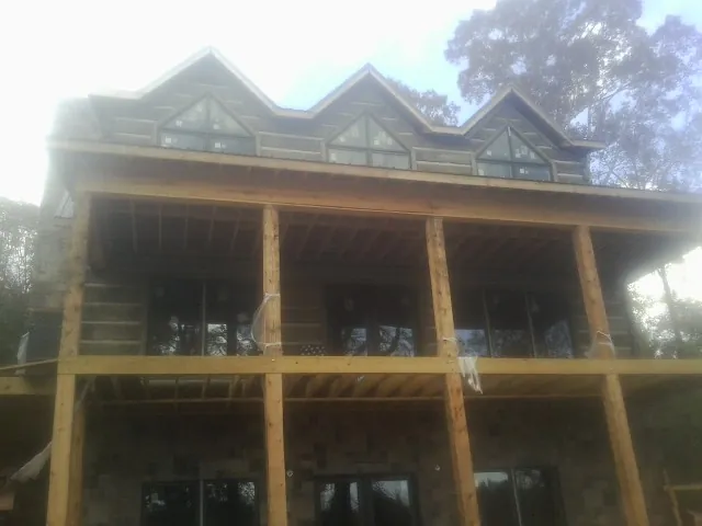 Dormers and porch framing on a large log home under construction — Roof Coating work by our crew in Lena